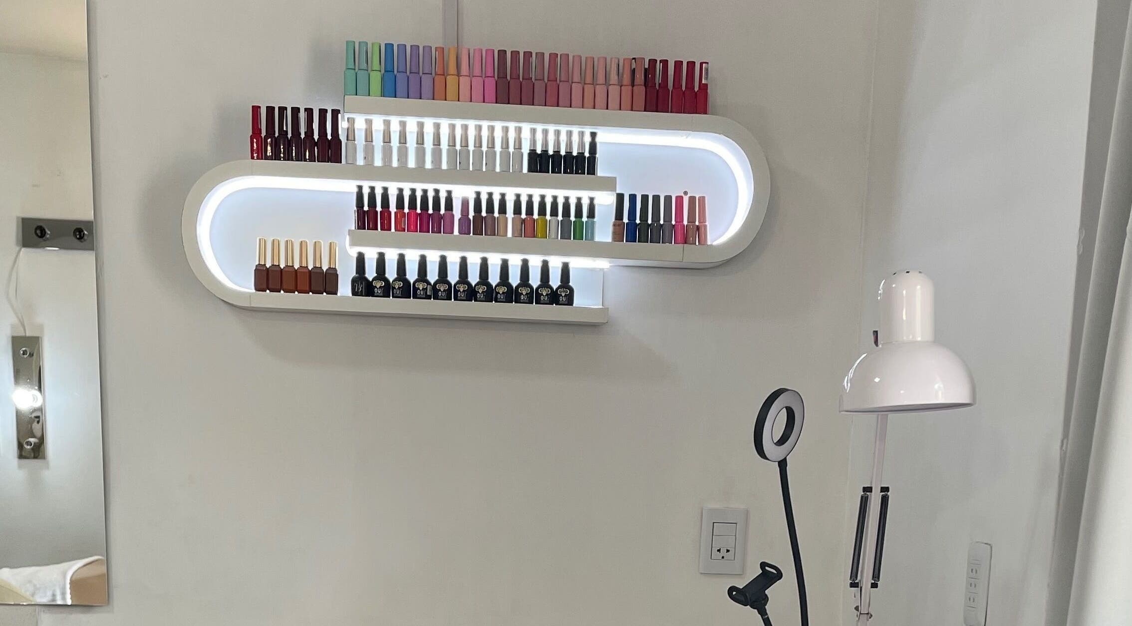 Estante de esmaltes iluminado en romSo, Luque, Central, PY, destacando variedad de colores.