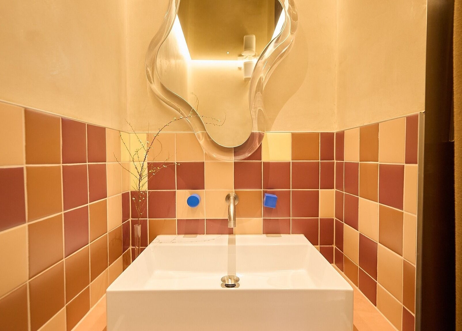 Sleek modern sink with artistic mirror and warm tiles at Sage Space, Darlinghurst, New South Wales, AU.