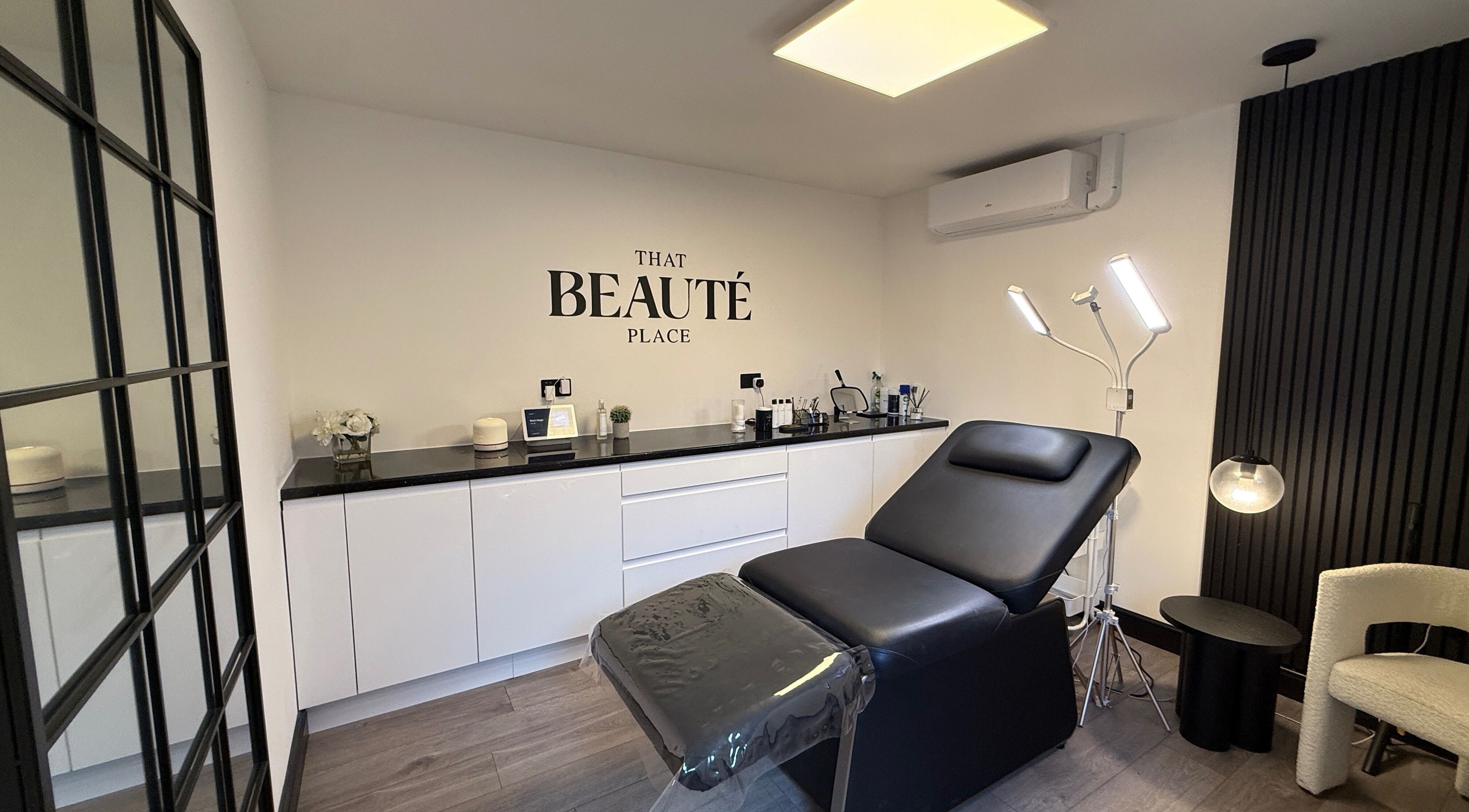 Chic treatment room at That Beaute Place, Alconbury, England, GB, featuring a modern black reclining chair.