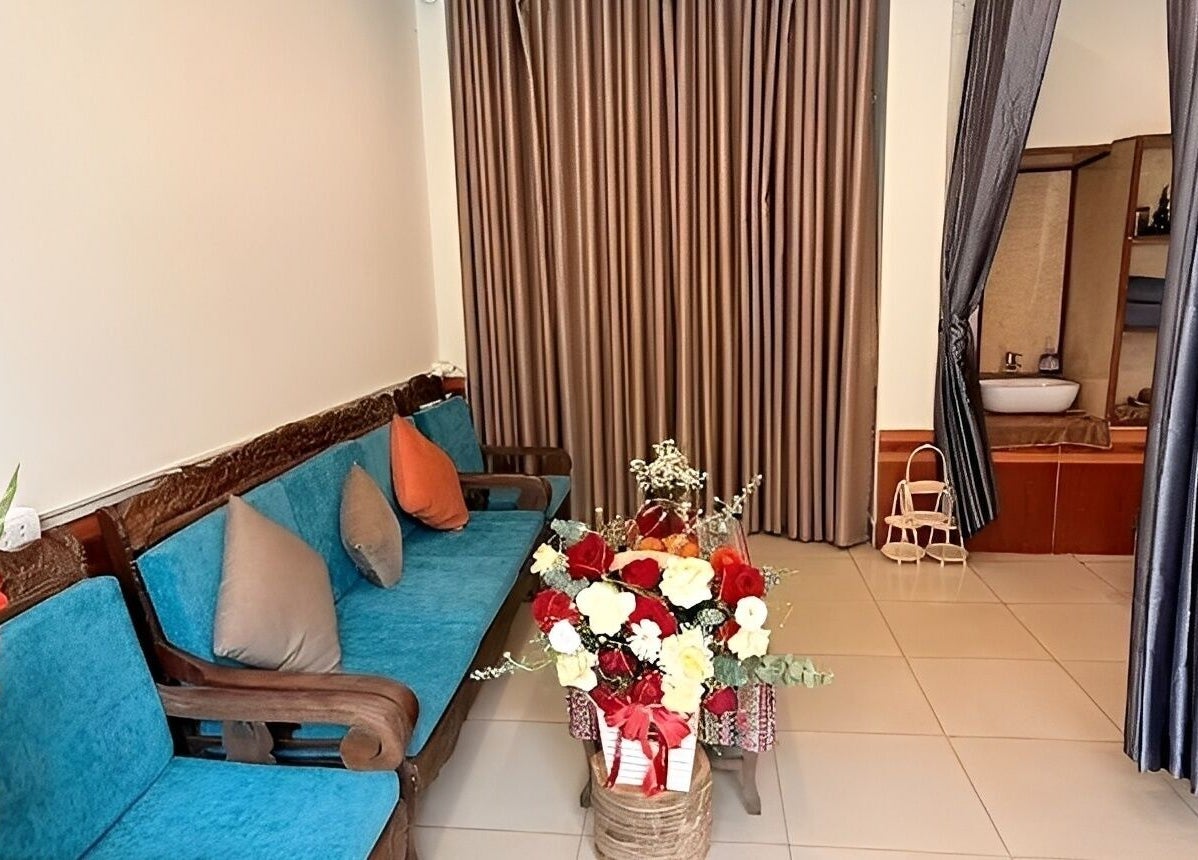 Phòng khách sang trọng tại Senviet Spa Care, Hà Nội, Hà Nội, VN với ghế xanh và hoa tươi sáng.