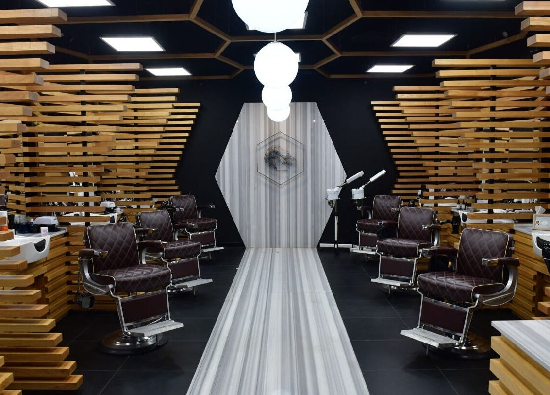 Chic interior of Adam Grooming Atelier - Brookfield Place, New York, New York, US with sleek wood accents and styling chairs.
