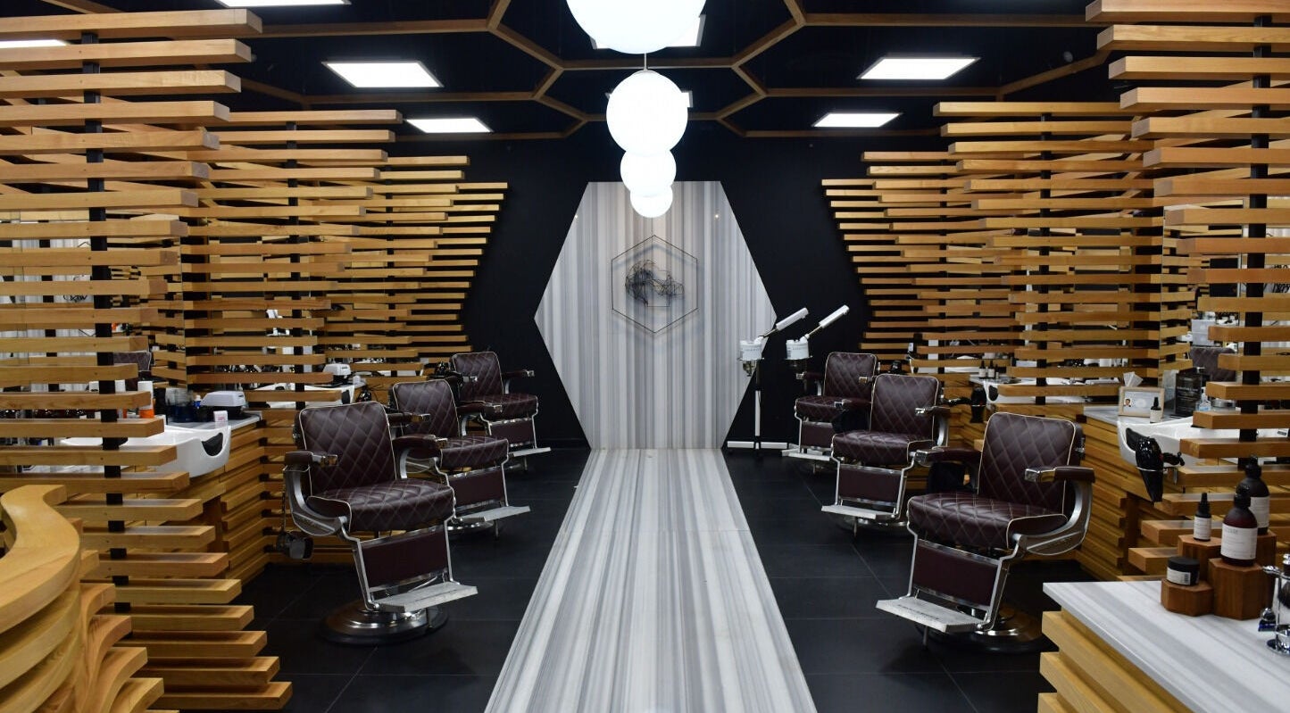 Chic interior of Adam Grooming Atelier - Brookfield Place, New York, New York, US with sleek wood accents and styling chairs.