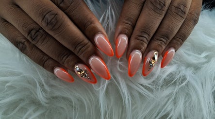 Stylish orange-tipped nails with sparkling gems from Maestra of Divine Nail Art Inc. in Brighton, St. George, VC.
