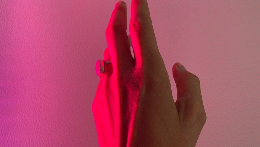 Hand with a ring bathed in pink light at Sports Care Therapy, London, GB.