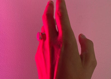 Hand with a ring bathed in pink light at Sports Care Therapy, London, GB.