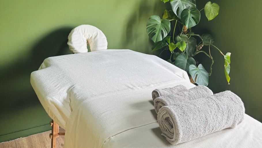 Rustige massagetafel bij Melohh Massage (for women only) in Amsterdam, Noord-Holland, NL, omlijst door groene planten.