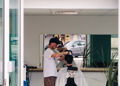 Barber styling customer at Wakes Barbershop, Newquay, England, GB. Clean, modern interior.