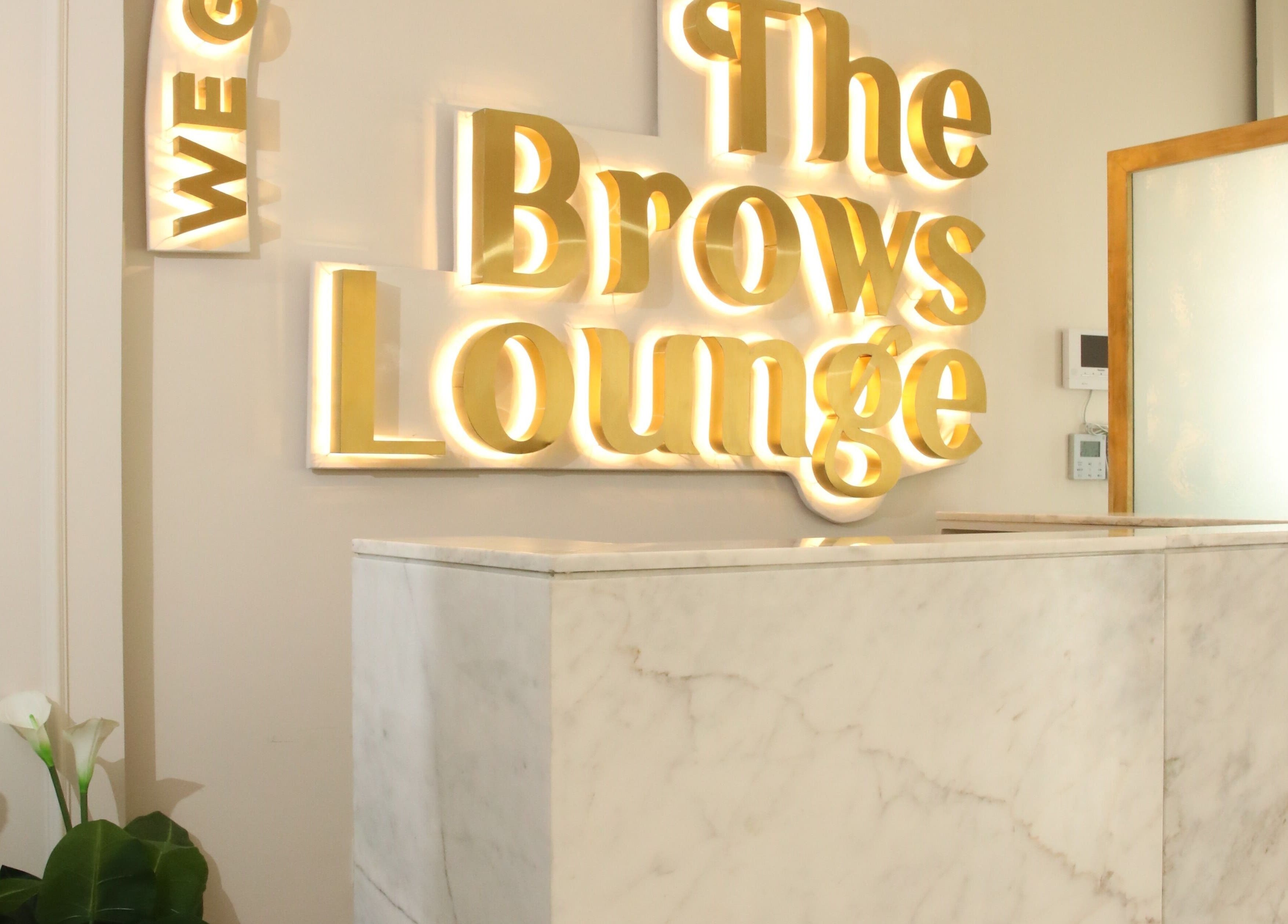 The Brows Lounge reception in الرياض, منطقة الرياض, SA features a marble counter and glowing sign.