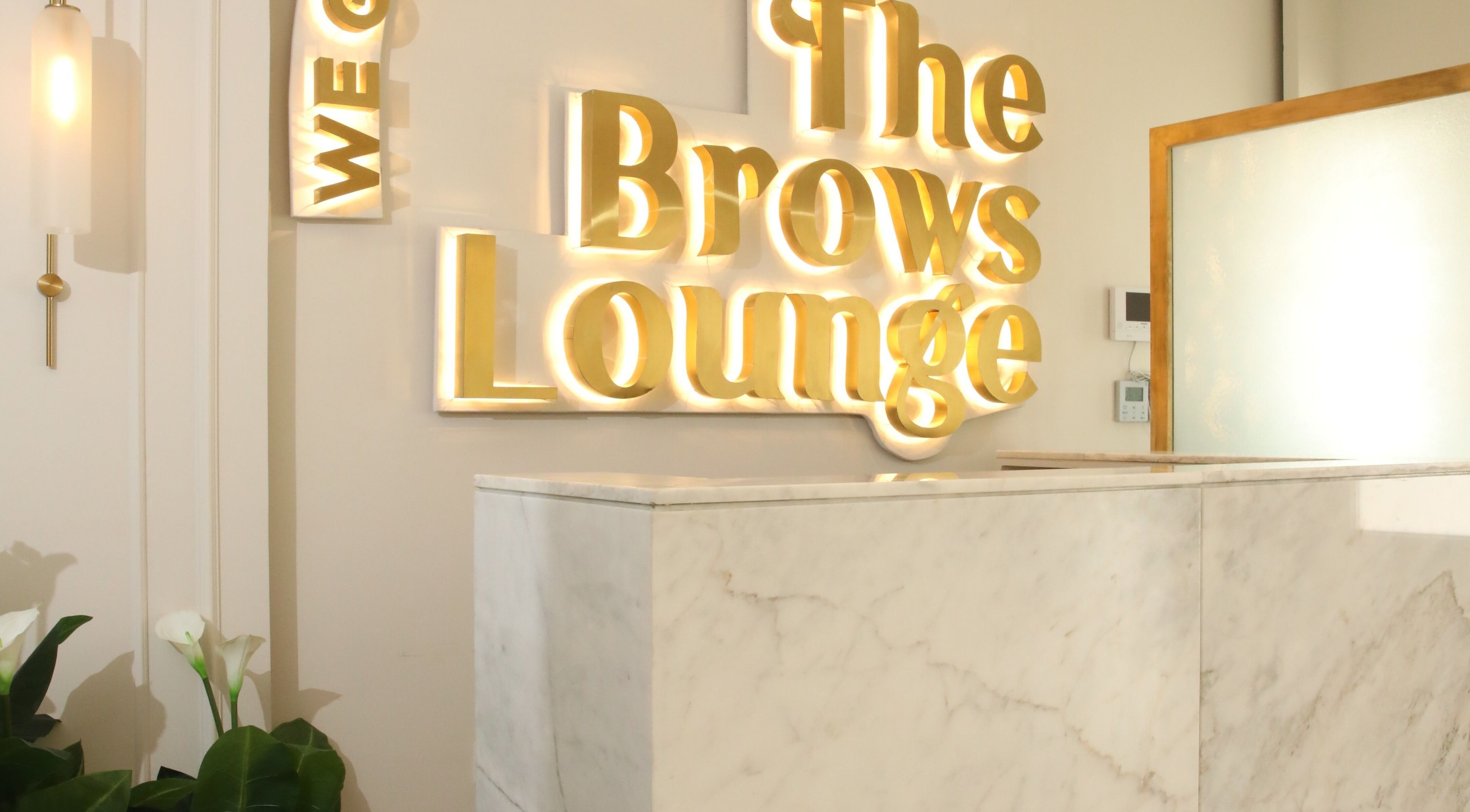 The Brows Lounge reception in الرياض, منطقة الرياض, SA features a marble counter and glowing sign.