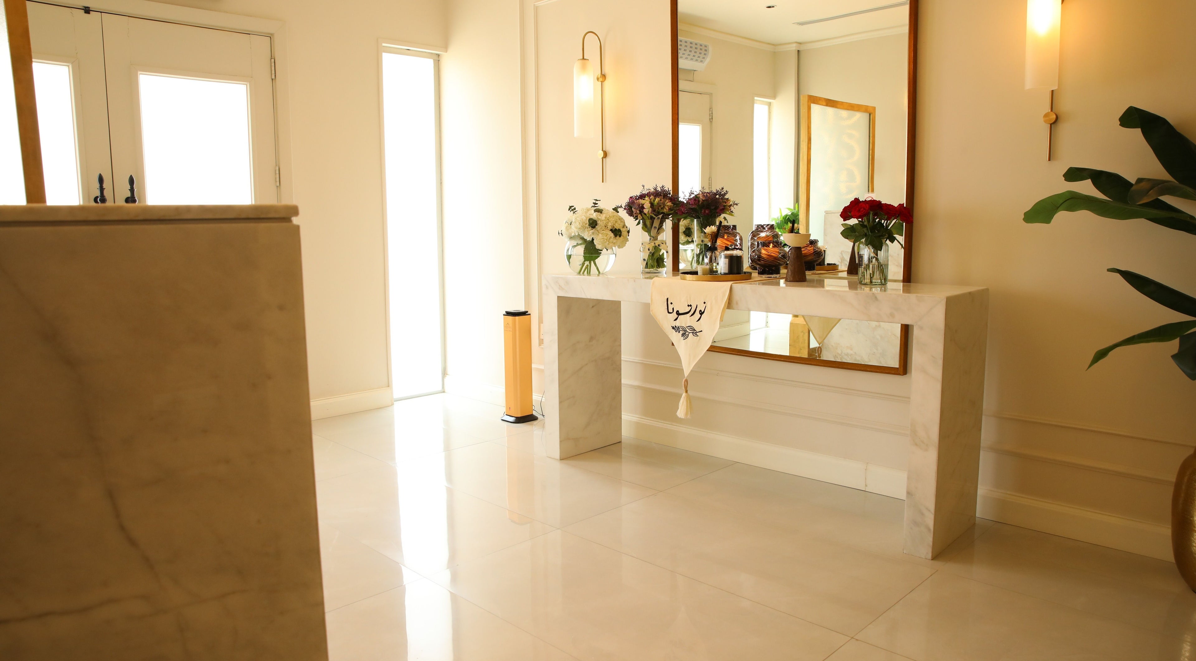 Chic entryway at The Brows Lounge, الرياض, منطقة الرياض, SA with a marble table and floral decor.