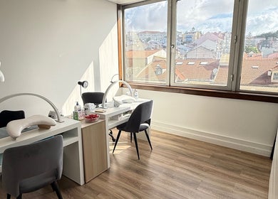 Interior iluminado da VA Nails & Design em Lisboa, Lisboa, PT, com vista urbana e mesas de design moderno.