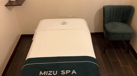Massage room at Mizu Spa Massage - Delray Beach, Florida, US, featuring a plush bed and elegant decor.