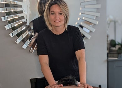 Therapist at Rekas holistic massage performing a massage in Woking, England, GB. Relaxing ambiance with mirror decor.