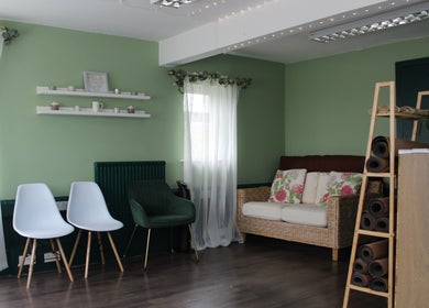 Cozy seating area at Ene Holistics, Warrington, England with green walls and natural light.
