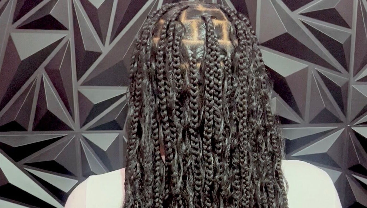 Intricate braids at Luxlooks.bylea in Savanna La Mar, Westmoreland Parish, JM against geometric backdrop.