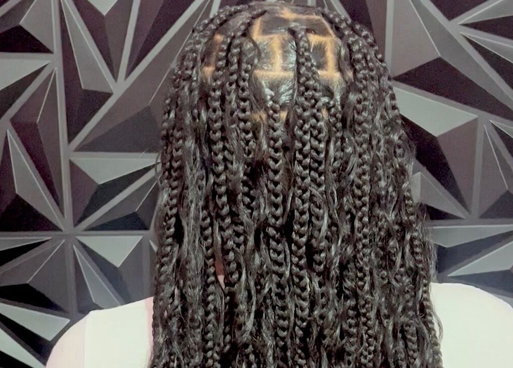 Intricate braids at Luxlooks.bylea in Savanna La Mar, Westmoreland Parish, JM against geometric backdrop.