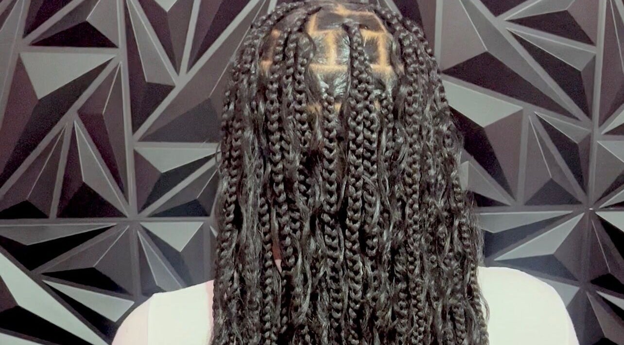 Intricate braids at Luxlooks.bylea in Savanna La Mar, Westmoreland Parish, JM against geometric backdrop.