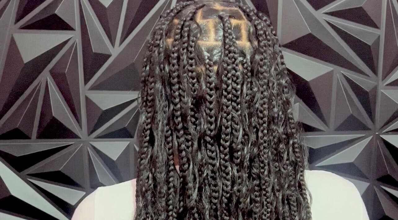 Intricate braids at Luxlooks.bylea in Savanna La Mar, Westmoreland Parish, JM against geometric backdrop.