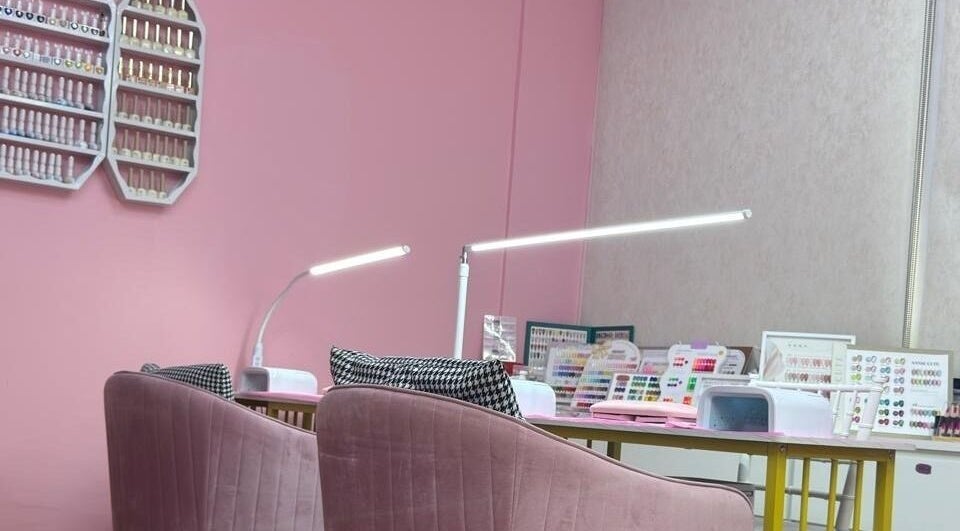 Stylish nail area at Aurora Beauty Women Salon in Dubai, AE featuring pink chairs and nail polish displays.