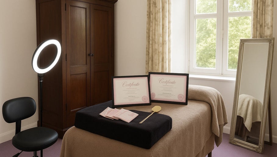 Relaxing Beauty Barn treatment room in Catton, England with spa bed, large mirror, and certificates.