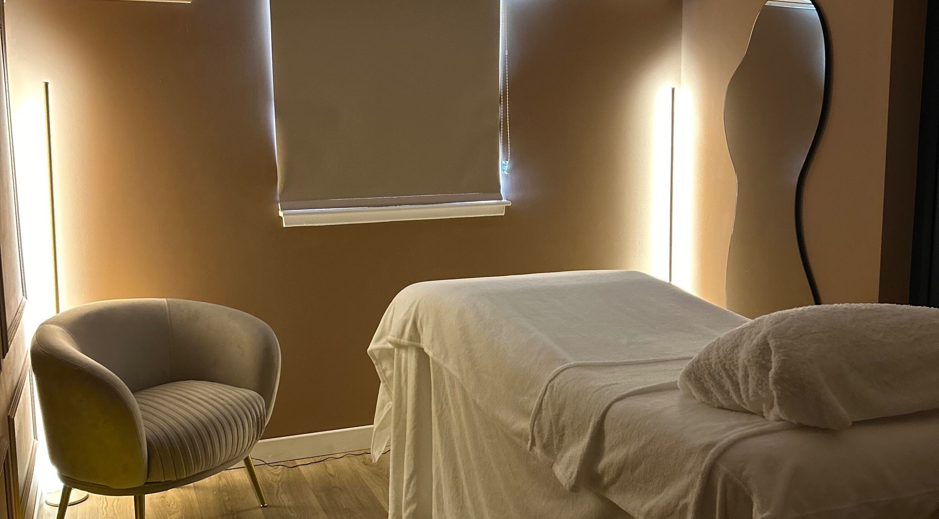 Calm treatment room at RS Skincare, Cumbernauld, Scotland, GB with a cozy chair and massage table.