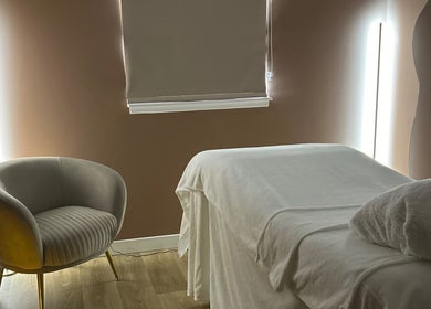 Relaxing treatment room at RS Skincare, Cumbernauld, Scotland, GB with cozy chair, bed, and soft lighting.