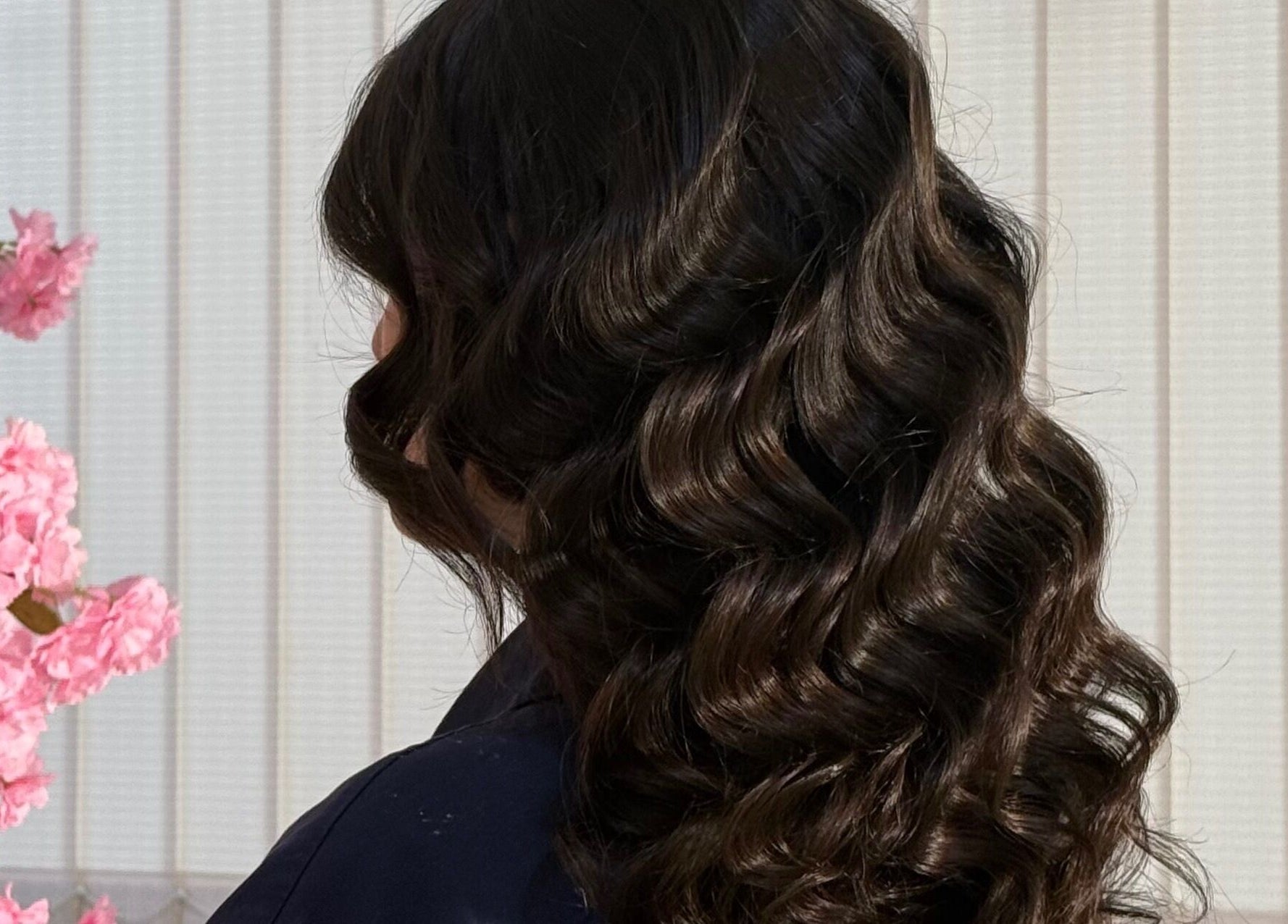 Elegant curls styled at Fatima beauty house, Aqaba, Aqaba Governorate, JO with pink blossoms background.