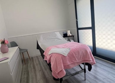 Sala de tratamiento en Beauty Láser, Montornès Del Vallès, Catalunya, ES, con cama cubierta de manta rosa.