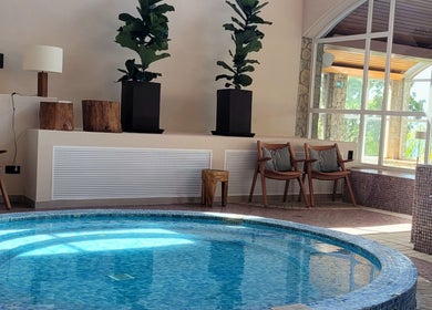 Piscina interior en AUA SPA Zel Costa Brava, TOSSA DE MAR, Catalunya, ES, rodeada de sillas y plantas.