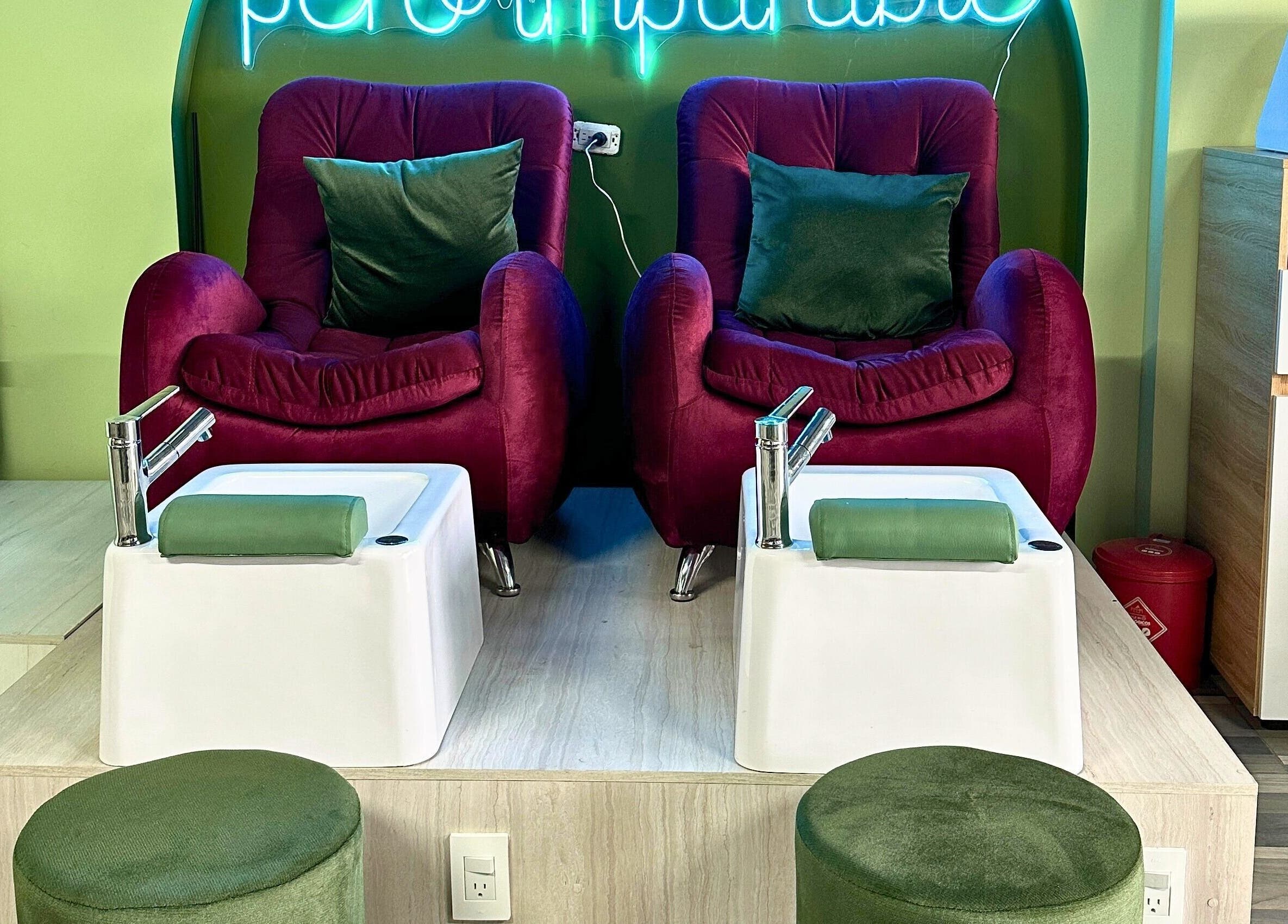 Zona de pedicura de Rafaelas Nails Spa en Bogotá, Bogotá, CO, con sillas aterciopeladas y tinas elegantes.