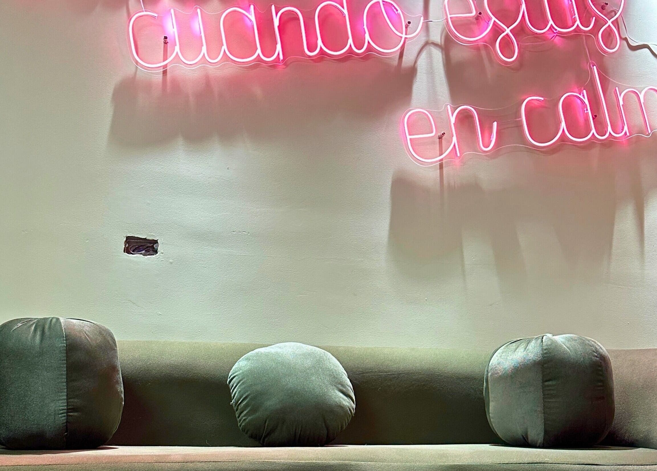 Espacio acogedor en Rafaelas Nails Spa, Bogotá, con sofá y letrero neón que refleja calma.