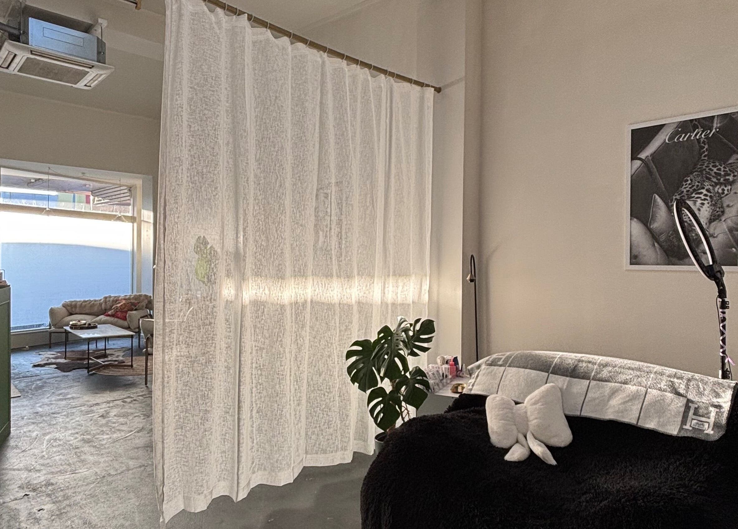 Relaxation space at Divine Aesthetics, Levin, NZ, featuring cozy seating, soft curtains, and ambient lighting.