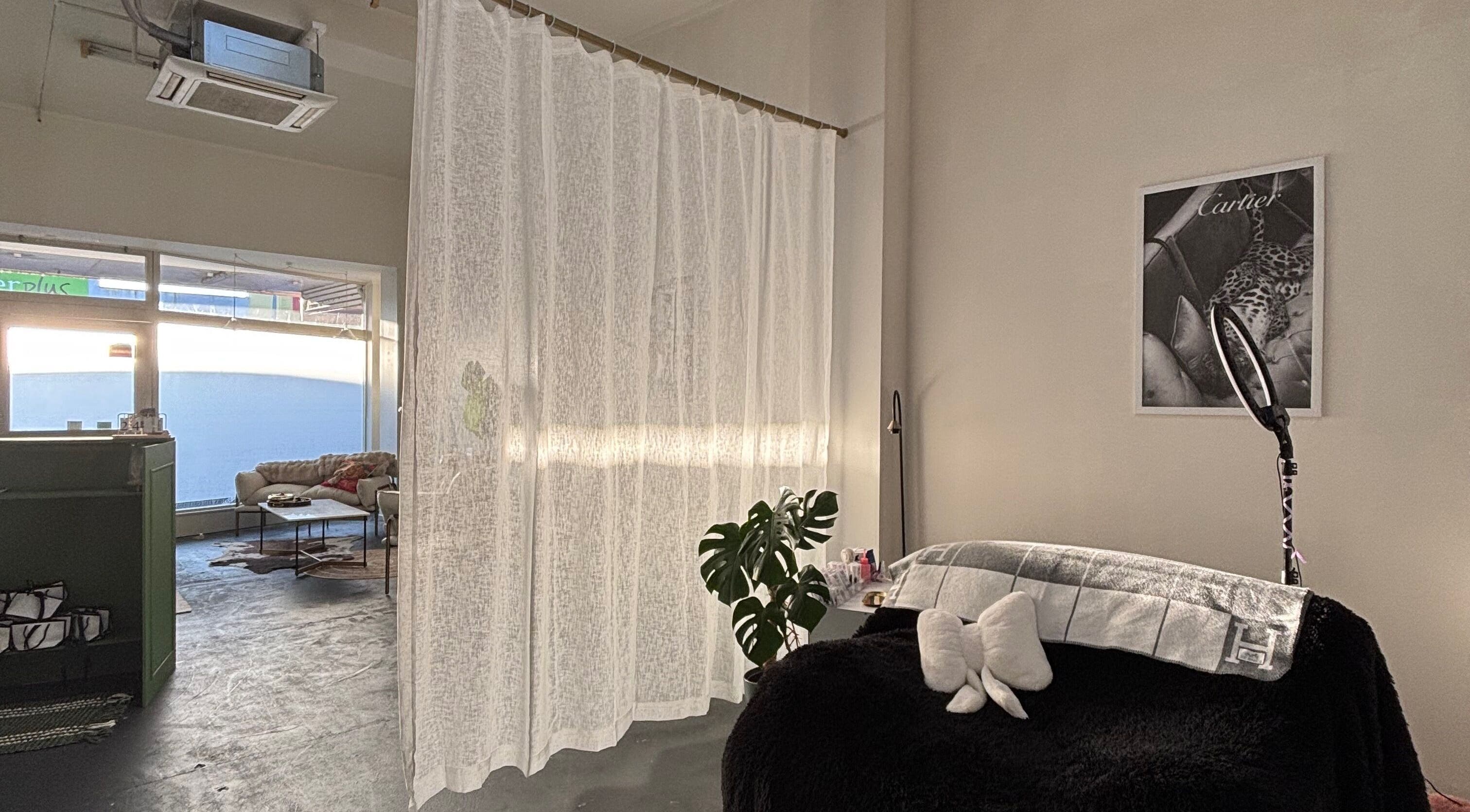 Relaxation space at Divine Aesthetics, Levin, NZ, featuring cozy seating, soft curtains, and ambient lighting.