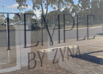 Reflection of Temple by Zyna signage on window in Moranbah, Queensland, AU.