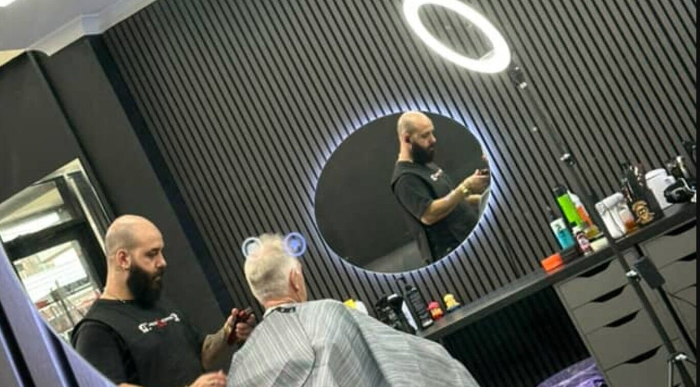 Stylist at Awesome Barbers in Melbourne, Victoria, AU, works with a client in a sleek, modern setting.