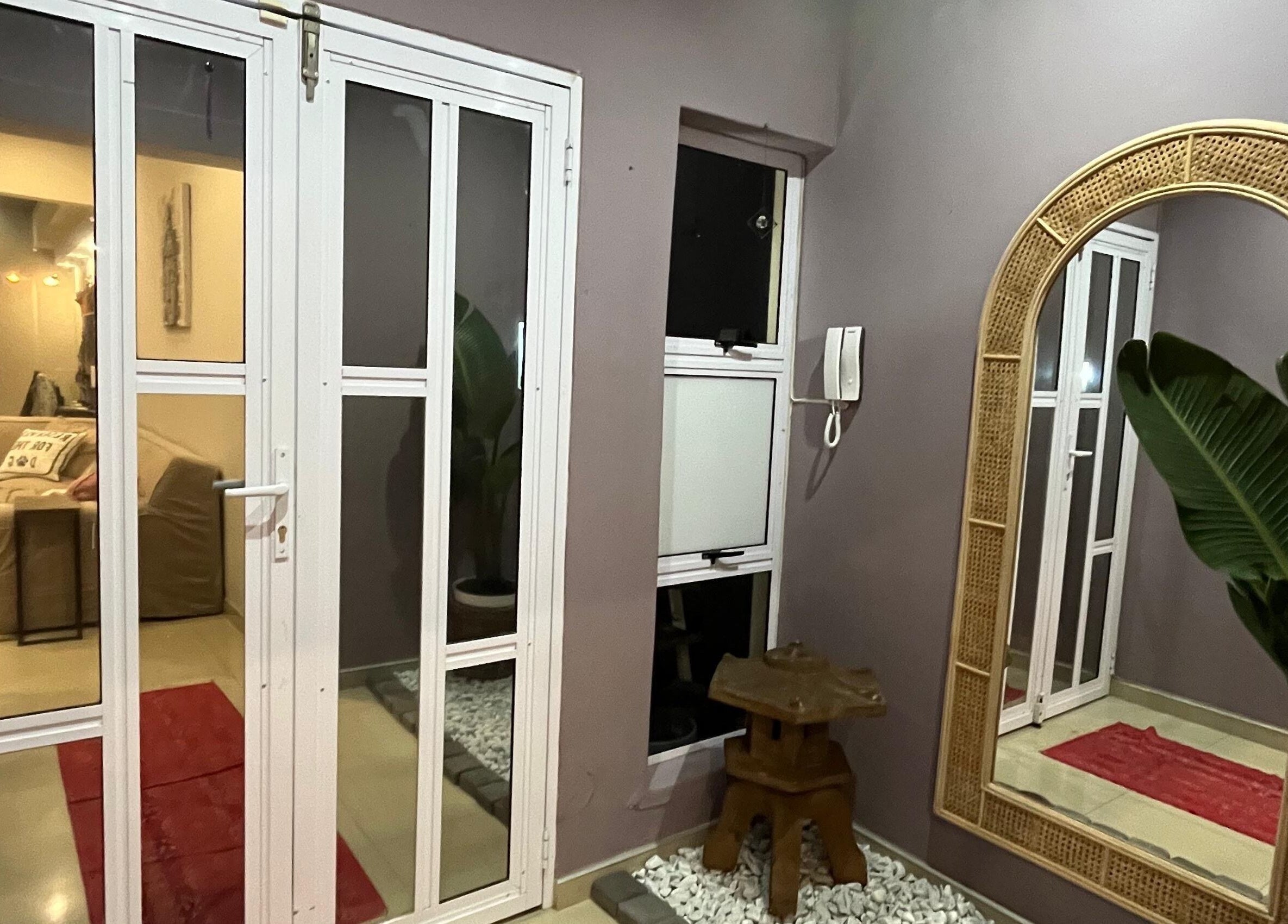 Stylish entrance at Jackie Bee Aesthetics, Ballito, Kwazulu-natal, ZA with rattan mirror and lush plant.