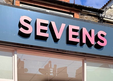 Sevens venue sign in Cardiff, Wales, GB with bold pink letters on a blue background.