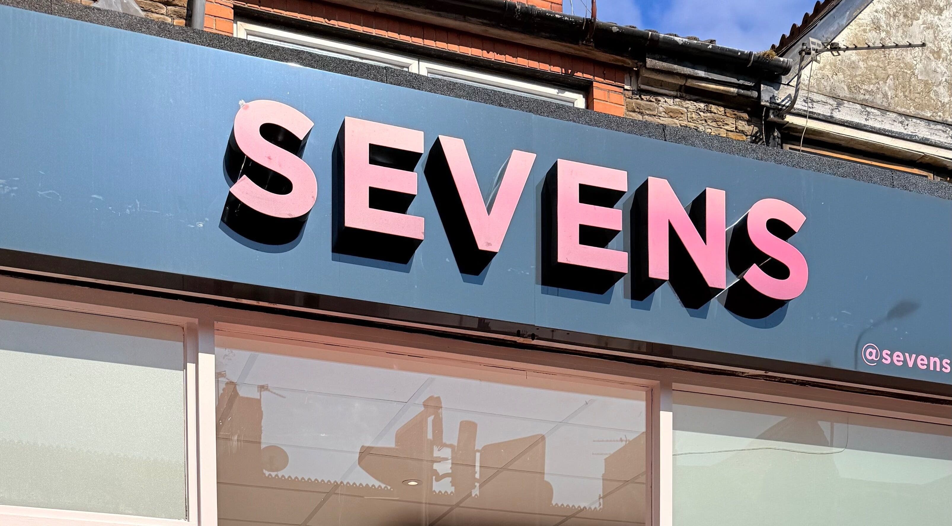 Sevens venue sign in Cardiff, Wales, GB with bold pink letters on a blue background.
