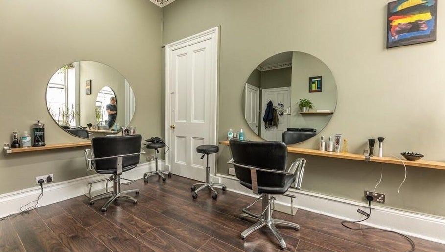 Contemporary salon interior at Scott’s Hairdressing, Glasgow, Scotland, GB with chic mirrors and styling chairs.