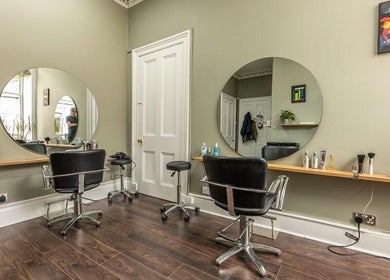 Contemporary salon interior at Scott’s Hairdressing, Glasgow, Scotland, GB with chic mirrors and styling chairs.