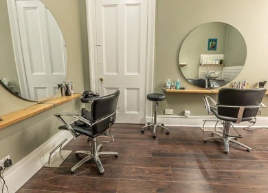 Modern salon interior at Scott’s Hairdressing, Glasgow, Scotland, GB, featuring sleek chairs and round mirrors.