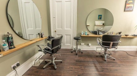 Modern salon interior at Scott’s Hairdressing, Glasgow, Scotland, GB, featuring sleek chairs and round mirrors.