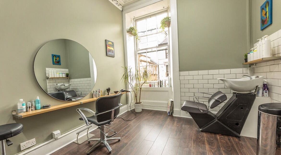 Interior of Scott’s Hairdressing in Glasgow, Scotland, GB, featuring a stylish workstation and washing area.