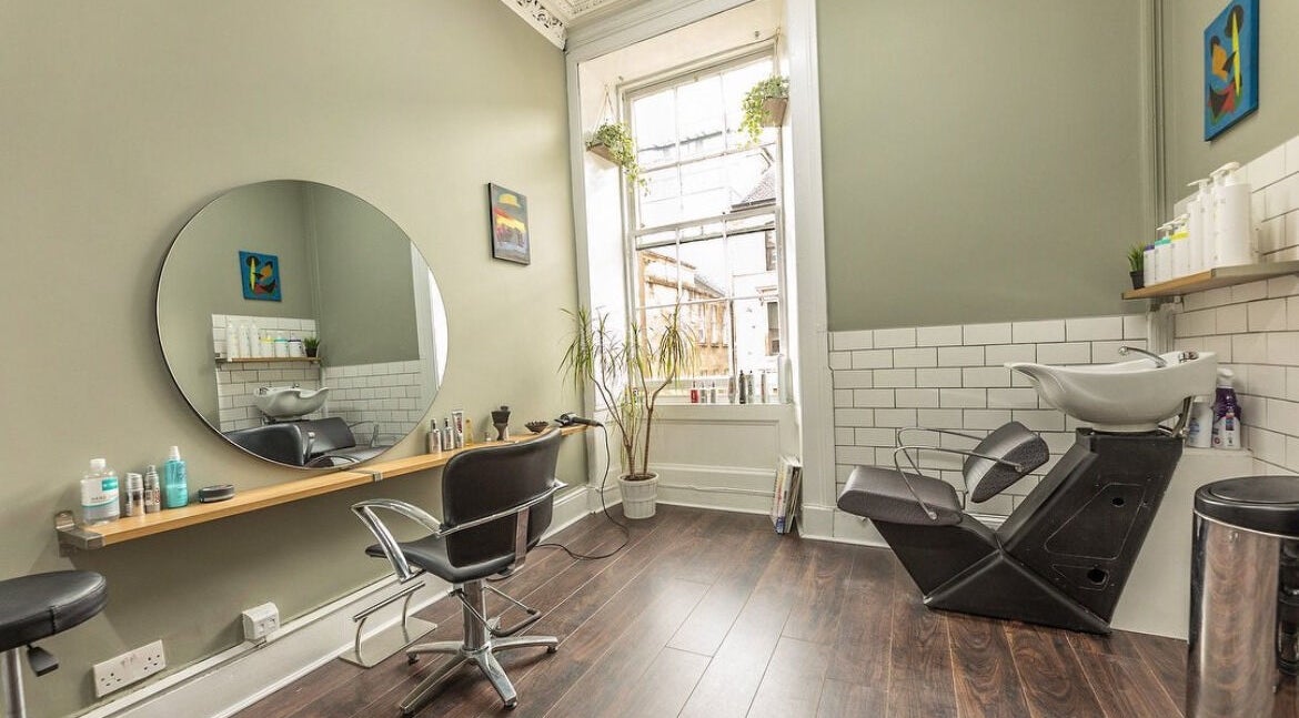 Interior of Scott’s Hairdressing in Glasgow, Scotland, GB, featuring a stylish workstation and washing area.