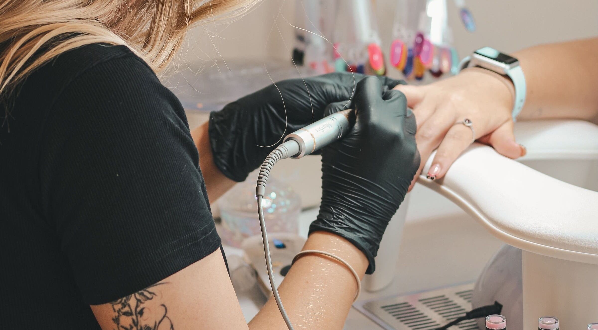 A nail technician at Nails by Norrie in Caernarfon, Cymru, GB, carefully shaping nails with precision tools.