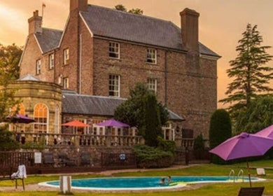 Peterstone Court Country House & Spa in Llanhamlach, Wales with poolside view at sunset.
