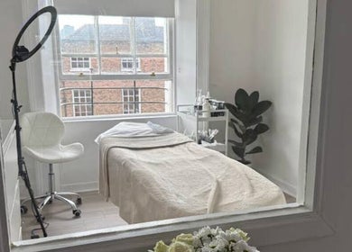 Cozy treatment space at Nonna Skincare in Dublin, County Dublin, IE featuring a plush bed and vibrant lighting.