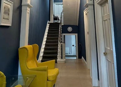 Elegant hallway at Nonna Skincare, Dublin, County Dublin, IE, featuring bold blue walls and yellow chairs.