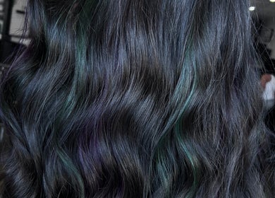 Close-up of wavy black hair with subtle colored highlights at Divine Beauty Parlor, San Antonio, Texas, US.