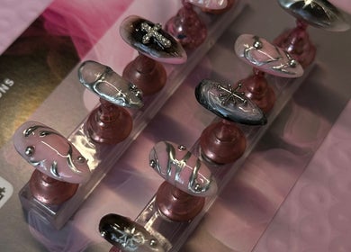 Intricate nail art display at Klaw Cartel, Birmingham, England, GB. Showcases detailed silver and pink designs.